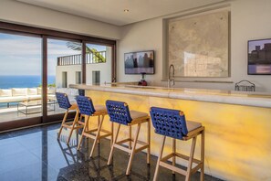 A modern bar area with a cityscape view, a television, and a large abstract painting. - 2 Villas, Luxury Amenities & Fully Staffed Service (Cabo San Lucas)