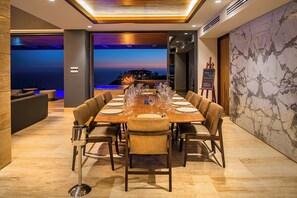 A dining room with a long table set for a meal, a view of the ocean, and a fireplace. - 2 Villas, Luxury Amenities & Fully Staffed Service (Cabo San Lucas)