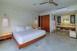 A modern hotel room with a large bed, a ceiling fan, a bathroom with a vanity and mirror, and a view of the outdoors. - 2 Villas, Luxury Amenities & Fully Staffed Service (Cabo San Lucas)