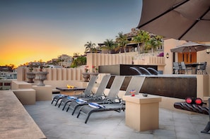 Una terrazza sul tetto con poltrone lounge, un braciere e vista sul tramonto.