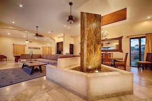A spacious living area with a central column, a sofa set, a dining table with chairs, and a chandelier. - Luxury Pedregal Villa Pairing with Stunning Ocean Views (Cabo San Lucas)