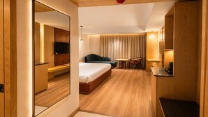 Een hotelkamer met een bed, zithoek en een televisie.
