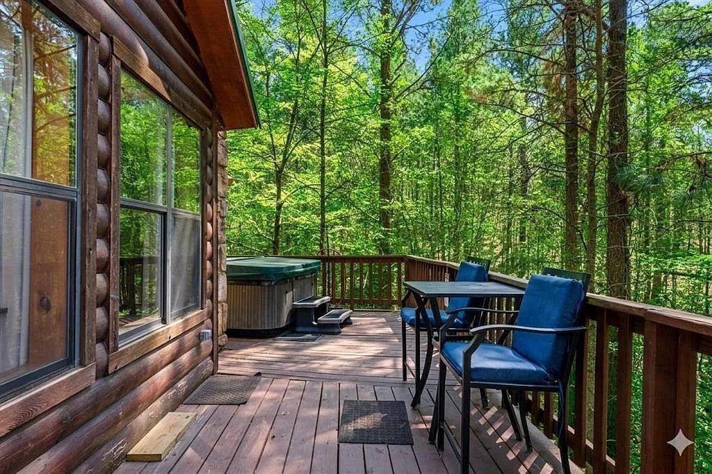 Une cabane en rondins dotée d’une terrasse, d’un espace salon extérieur et d’un jacuzzi.