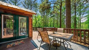 Eine Hütte mit einer Terrasse, einem Tisch und Stühlen.