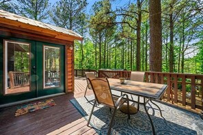 A cabin with a deck, a table, and chairs. - Whispering Pines Retreat - Covered Outdoor Lounge (Broken Bow)