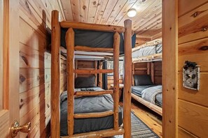 Interior de una cabaña de madera con literas y una puerta.