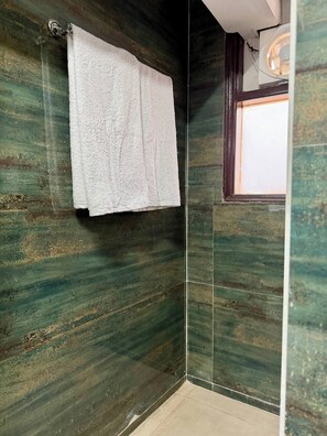 A bathroom with a green marble wall, a white towel hanging on a metal fixture, and a window with a view. - 401 - Designer Studio w/ Balcony - Golf Course Rd (Gurugram)