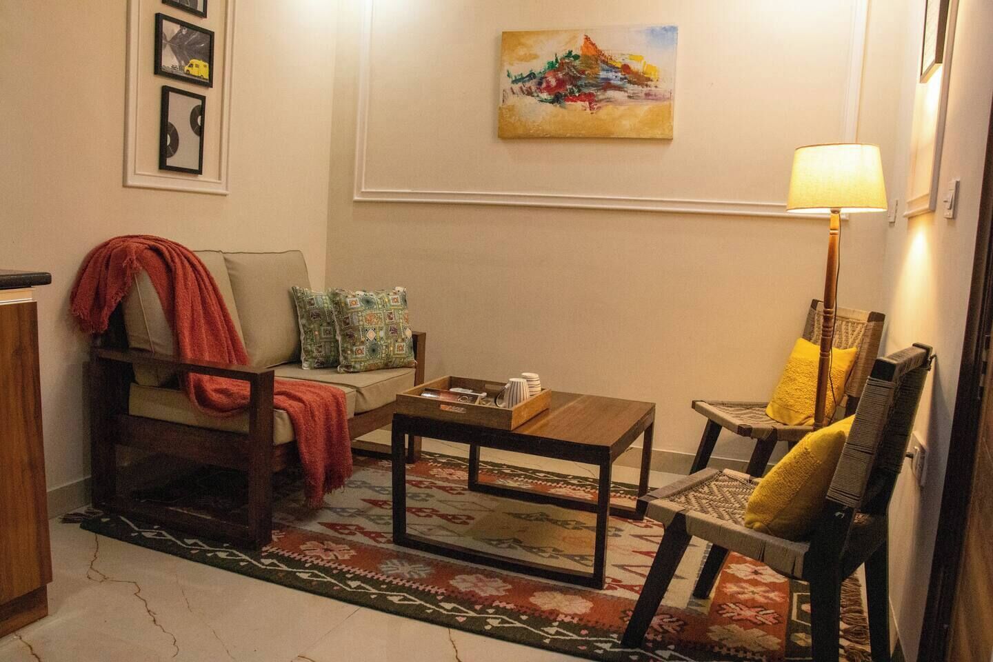Un salon avec un canapé, un fauteuil, une table basse et un tableau accroché au mur.