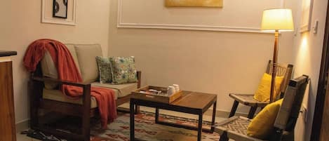 A living room with a sofa, armchair, coffee table, and a painting on the wall.