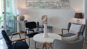 Un salon moderne avec une table ronde, deux chaises, une lampe et une grande œuvre d’art murale.