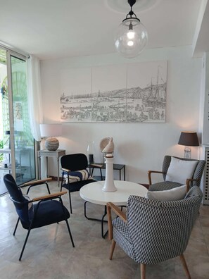 Ein modernes Wohnzimmer mit rundem Tisch, zwei Stühlen, einer Lampe und einem großen Wandbild.