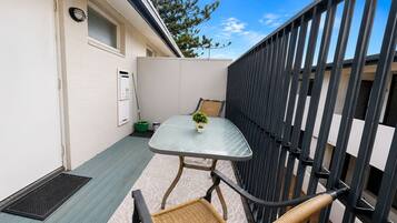 A small outdoor balcony with a table, chairs, and a potted plant.