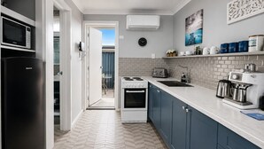 A modern kitchen with a microwave, stove, sink, and coffee machine.