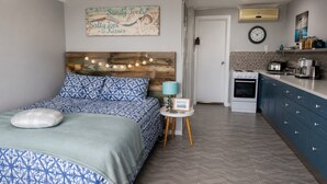 A bedroom with a bed, a bedside table, a lamp, and a wall clock.