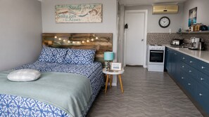 A bedroom with a bed, a bedside table, a lamp, and a wall clock.
