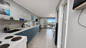 A modern kitchen with a large island, a built-in oven, and a view to a balcony.