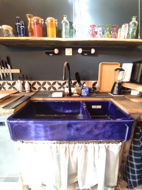 A kitchen with a blue sink, a black faucet, and a countertop with various kitchen items.