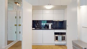 A compact kitchen with white cabinetry, a black countertop, and a built-in dishwasher. - Bright 1BR Kensington Flat-8 min Walk to Tube (London)
