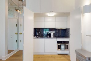 A compact kitchen with white cabinetry, a black countertop, and a built-in dishwasher. - Bright 1BR Kensington Flat-8 min Walk to Tube (London)
