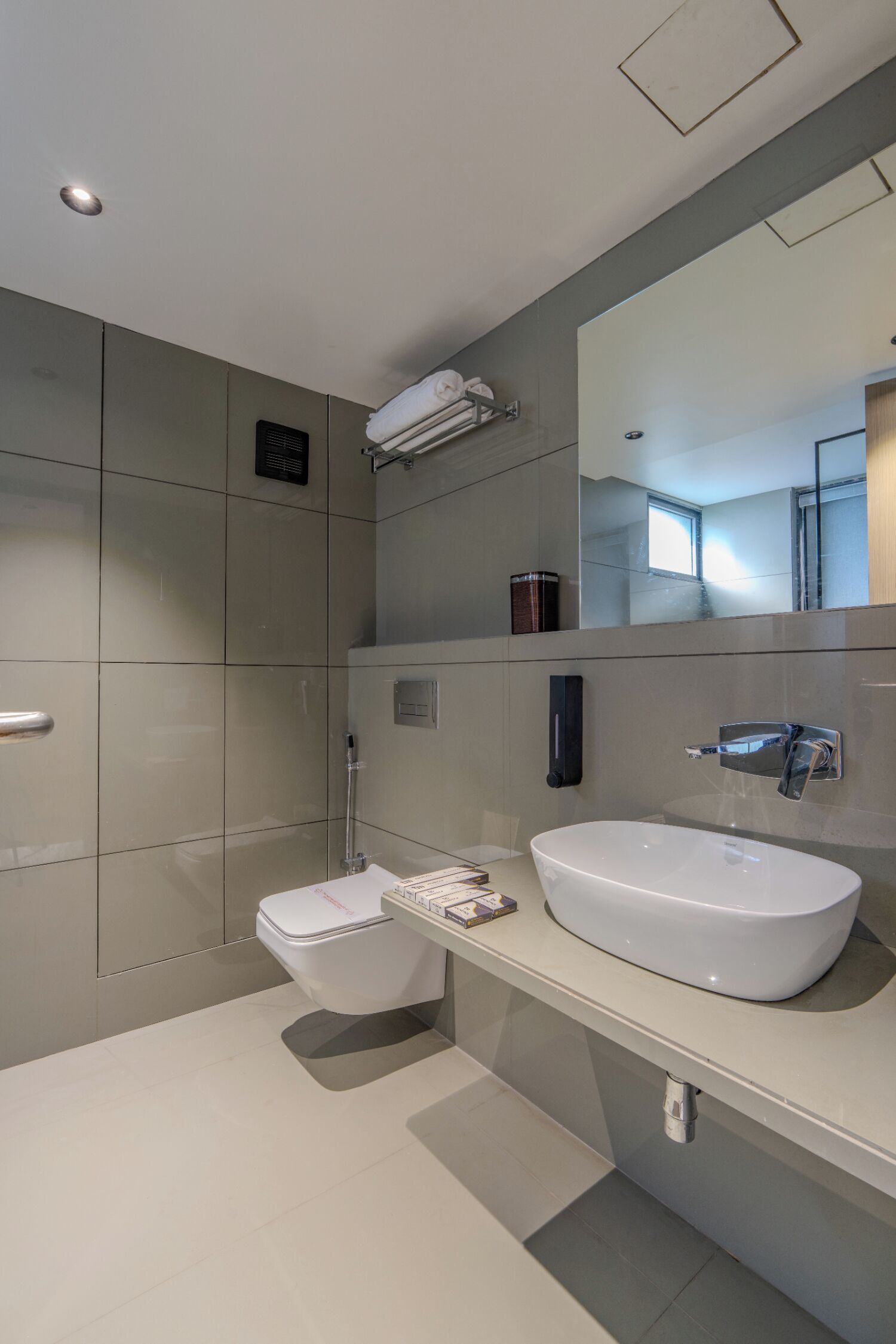 A modern bathroom with a large white sink, a toilet, and a mirror above the sink.