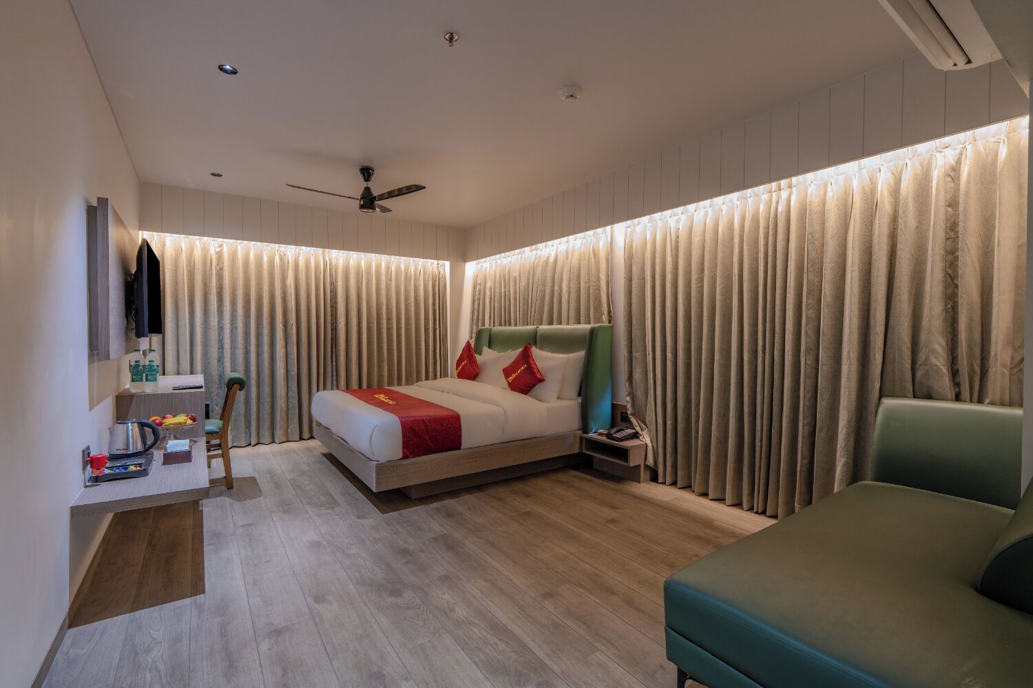 A modern hotel room with a bed, a desk, a chair, and a television.