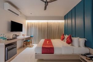 Habitación de hotel con cama, escritorio y silla, televisión y aire acondicionado.