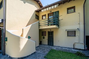 Ein Gebäude mit einer gewölbten Außenwand, einem kleinen Balkon mit Metallgeländer und einer Tür mit Fenster.