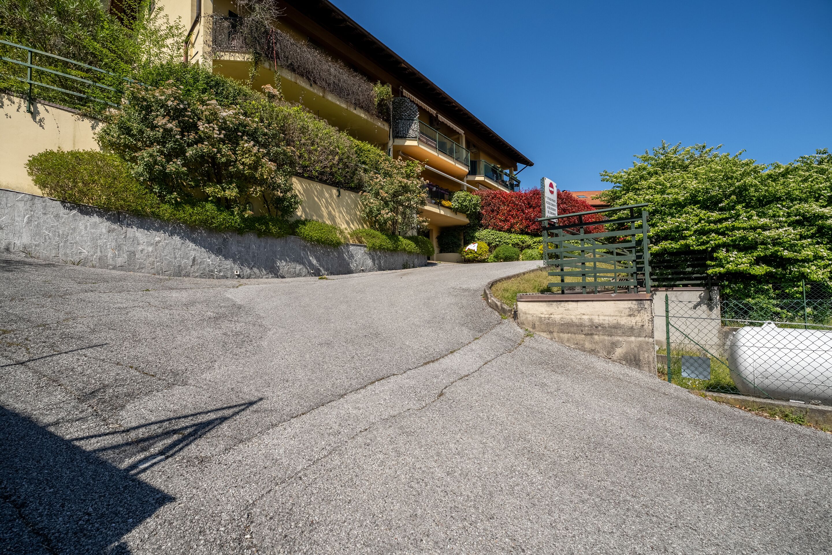 Un immeuble résidentiel doté de nombreux balcons, d’une entrée sécurisée et d’une allée pavée.
