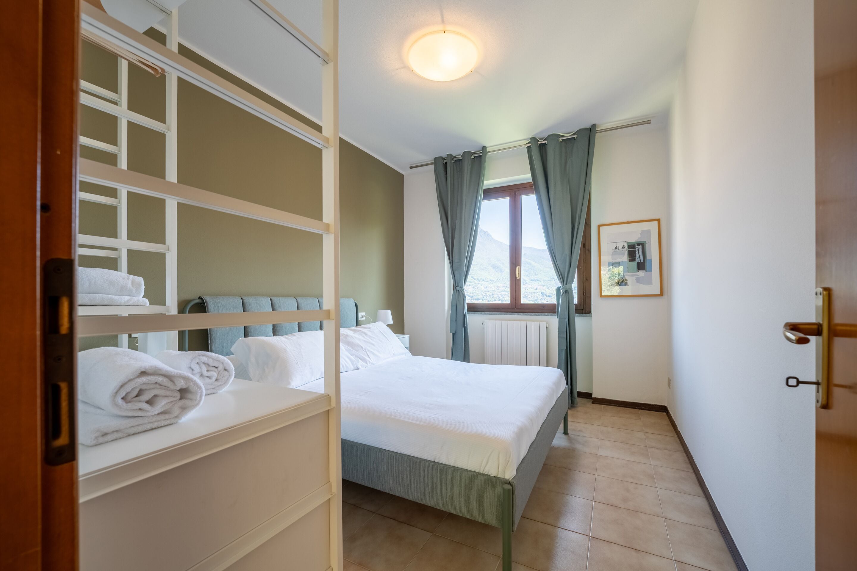 Une chambre d’hôtel avec un lit, une armoire et une fenêtre avec des rideaux.