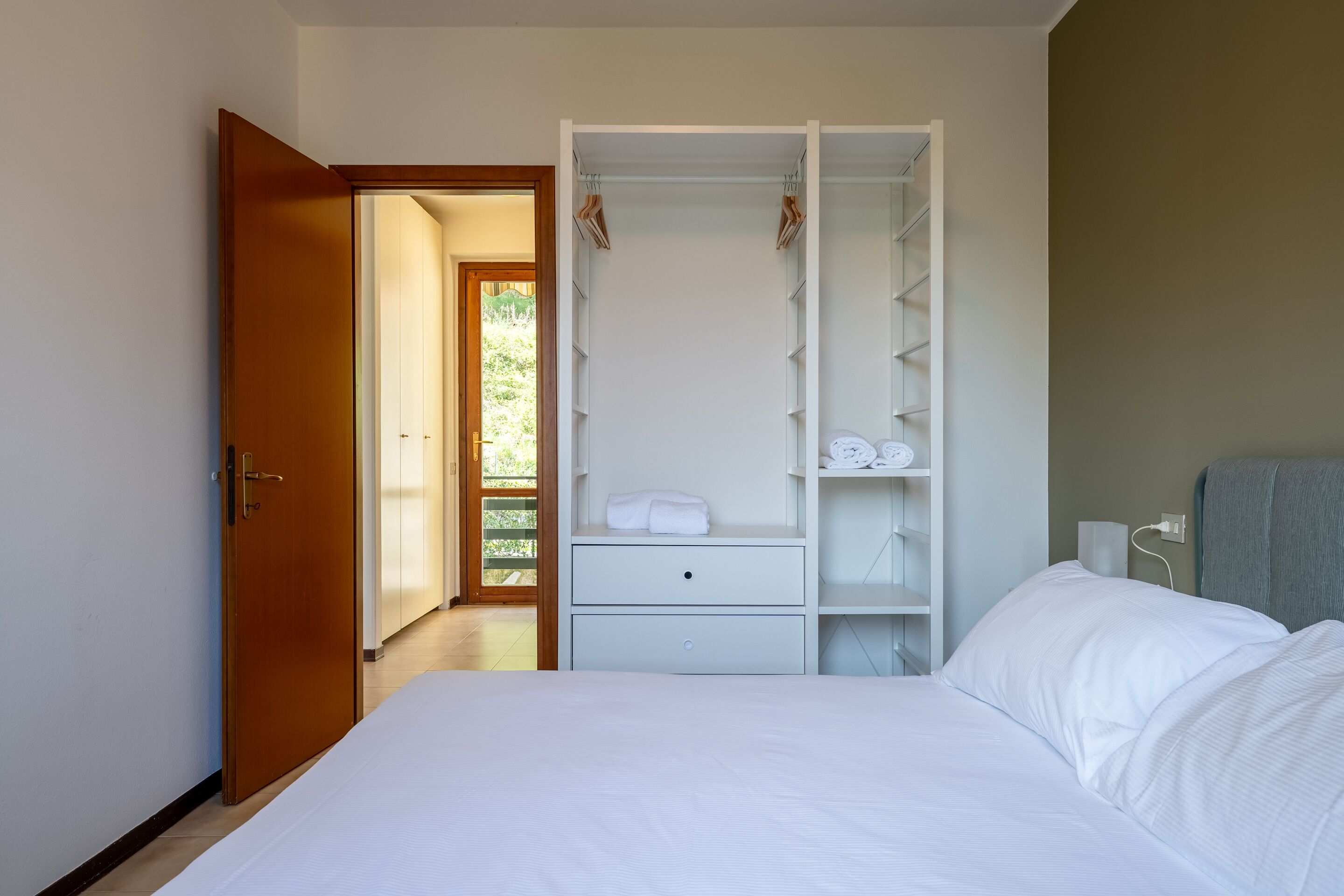 Une chambre à coucher avec un lit, une armoire et une salle de bain visible à travers une porte ouverte.