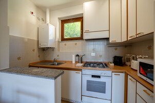 Cocina compacta con estufa a gas, horno y microondas integrado.