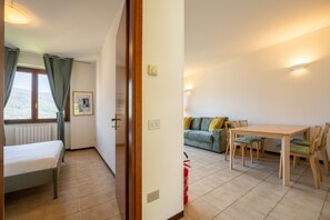 Ein Zimmer mit einem Bett, einem Esstisch mit Stühlen, einer Couch und einem Fenster mit Vorhängen.