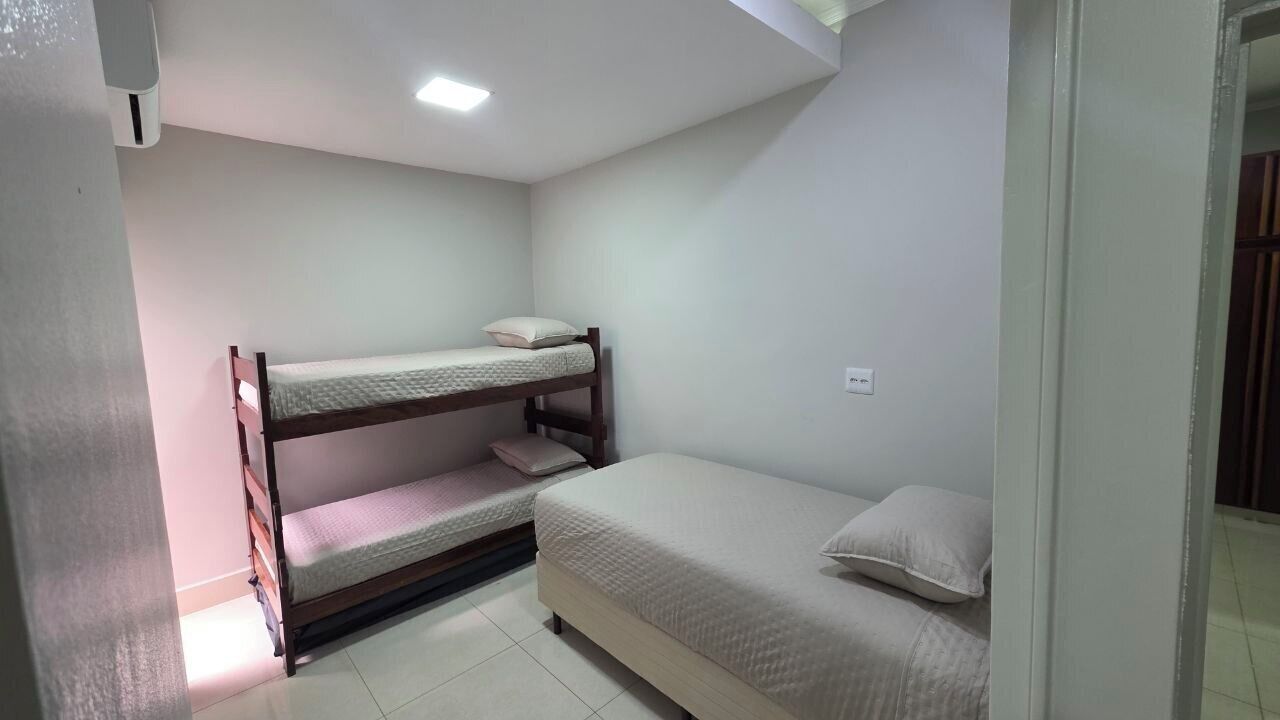 Un alojamiento pequeño con una cama doble y una cama individual, paredes blancas y suelo de baldosas.