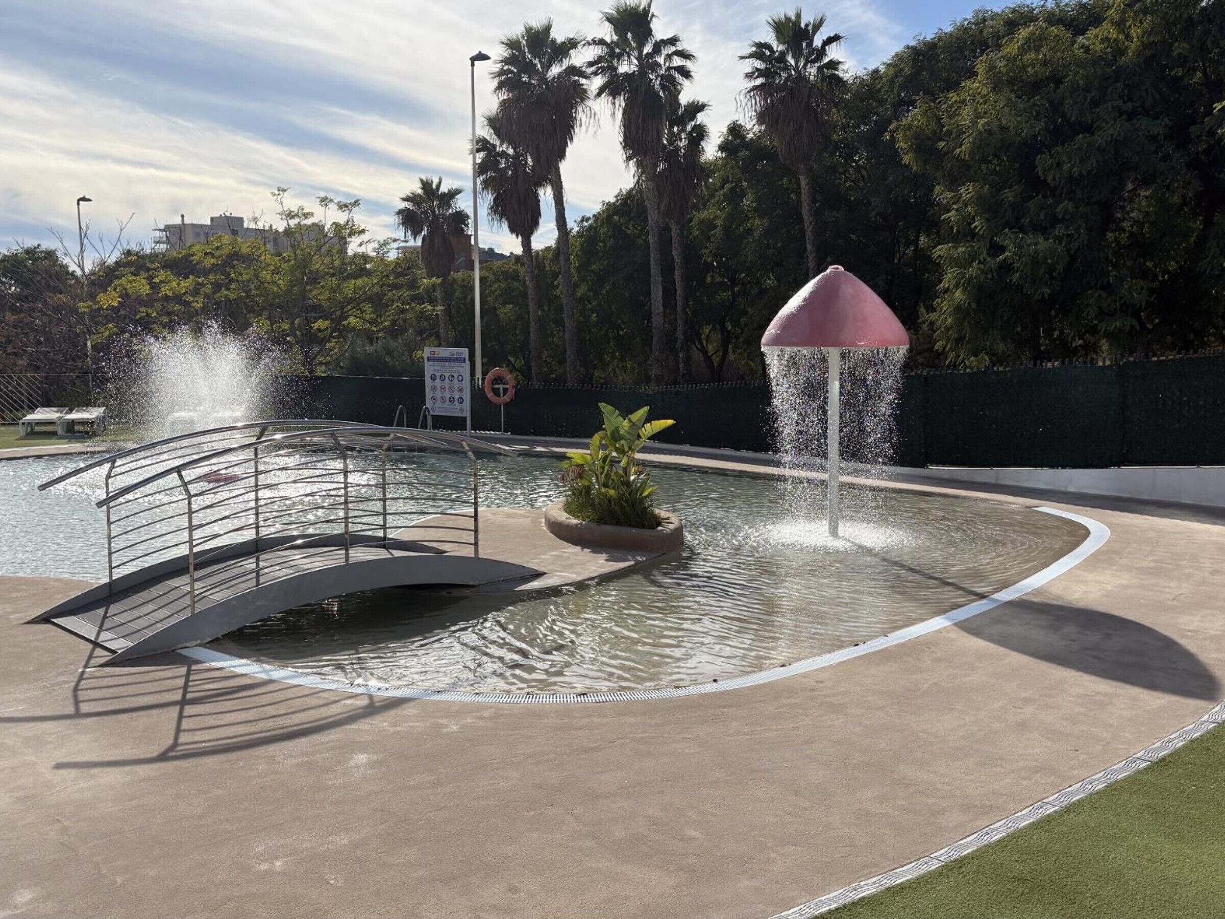 A swimming pool with a fountain, a diving board, and a lifebuoy.