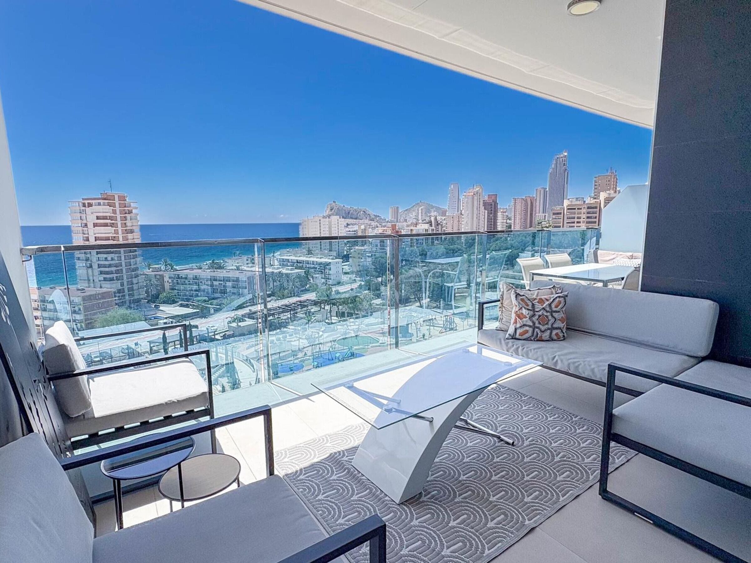 Ein Balkon mit Blick auf die Stadt, moderne Möbel und Geländer aus Glas.