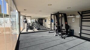 A gym with exercise equipment, a weightlifting area, and a view of the outside. - Modern apartment with panoramic sea view (Benidorm)