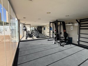 A gym with exercise equipment, a weightlifting area, and a view of the outside. - Modern apartment with panoramic sea view (Benidorm)