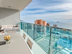 A balcony with a glass railing overlooking a pool and the sea. - Modern apartment with panoramic sea view (Benidorm)