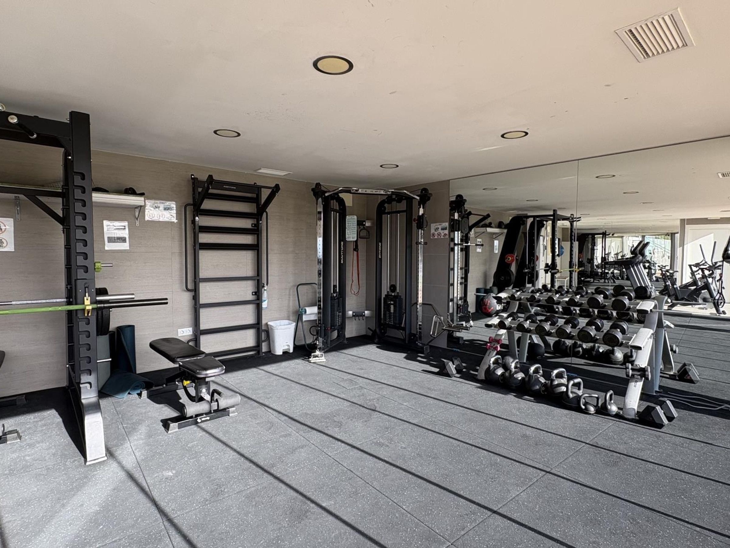 A gym with weightlifting equipment, benches, and dumbbells.