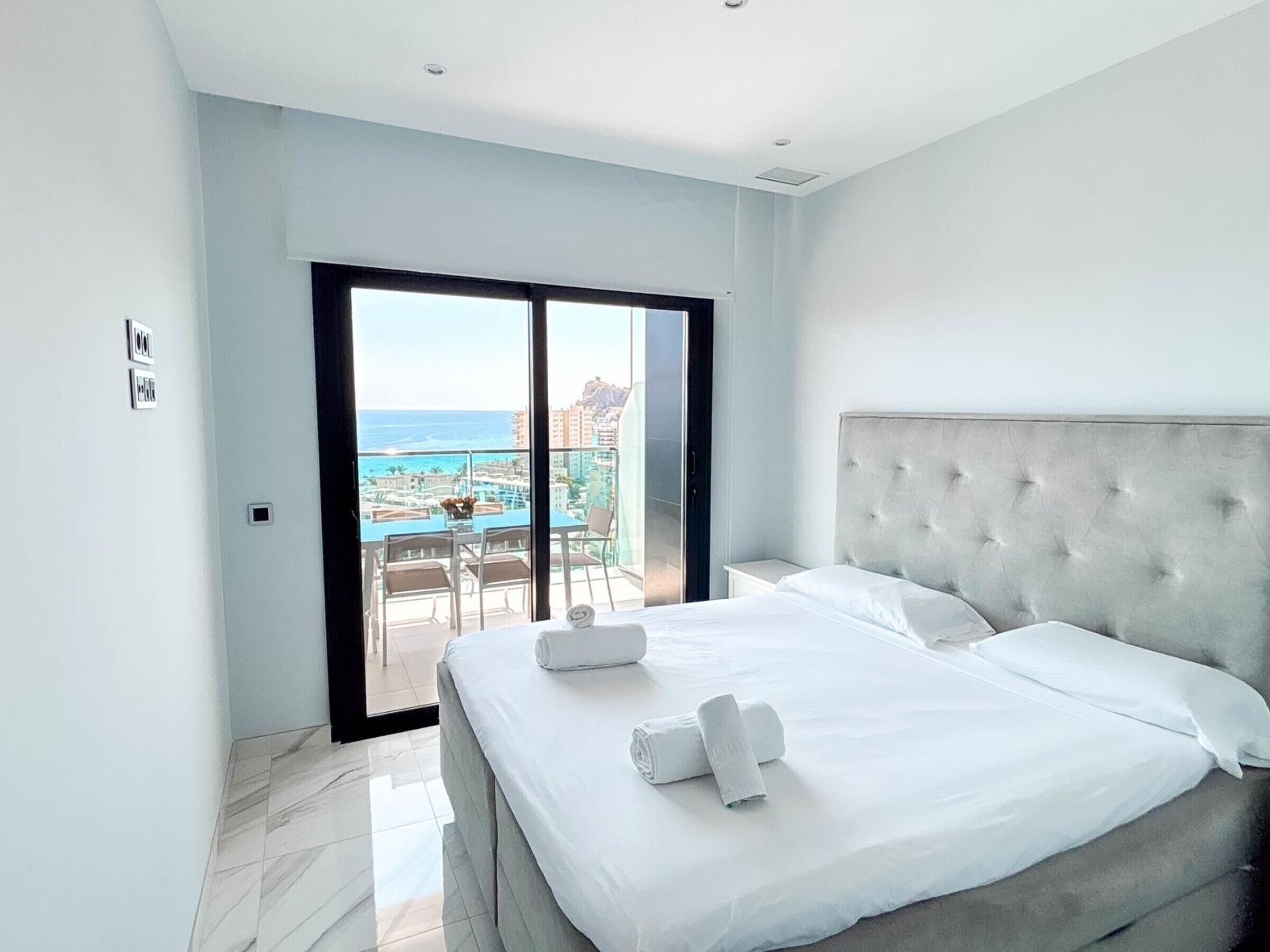 Une chambre d’hôtel avec un grand lit, une vue sur l’océan et un balcon équipé d’une table et de chaises.