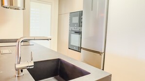 Eine moderne Küche mit Spüle aus Edelstahl, Backofen und Kühlschrank.