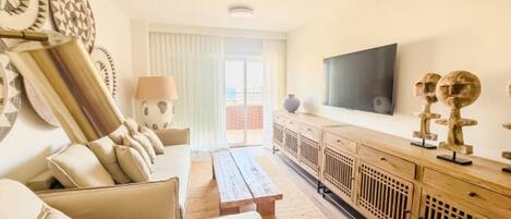 A modern living room with a sofa, a coffee table, a TV mounted on the wall, and decorative items on the sideboard.