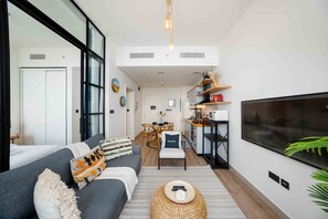 Ein modernes Wohnzimmer mit einer Couch, einem Fernseher und einer Küche im Hintergrund.