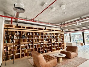 Ein großzügiger Leseplatz mit einer großen Bücherwand, Ledersesseln und einem Couchtisch.