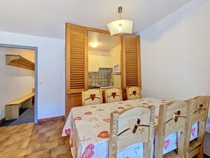 Ein Zimmer mit einem hölzernen Bett, einem Tisch und einem Stuhl mit herzförmigen Rückenlehnen.