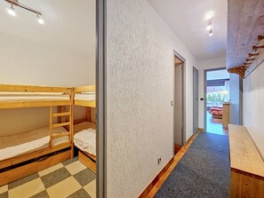 A corridor with bunk beds, a checkered floor, a wooden bench, and a door leading to an outdoor area. - Apartment with parking - 6 guests (La Clusaz)