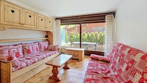 Una sala de estar acogedora con un sofá y una mesa de madera, y vistas al exterior.