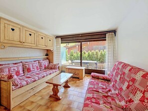 Ein gemütliches Wohnzimmer mit einem Holzdile und einem Holztisch, Blick ins Freie.