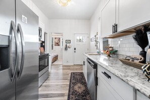 Eine moderne Küche mit Edelstahlgeräten, einer Marmorarbeitsplatte und Blick in den angrenzenden Wohnbereich.