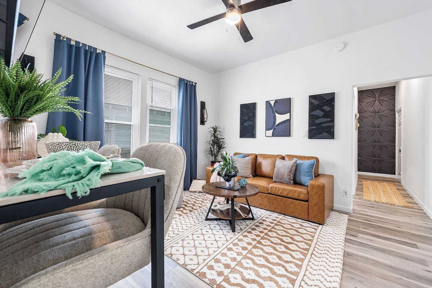 A modern living room with a sofa, coffee table, and a dining area with a table and chairs.